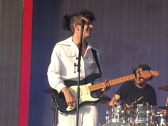 a man standing next to a guitar on top of a stage