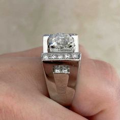 a close up of a person's hand holding a ring with a diamond on it