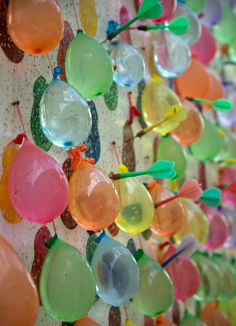 colorful glass spoons are hanging on a wall