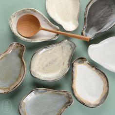 several different types of seashells with a wooden spoon in the middle one is empty