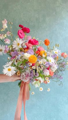 a woman holding a bouquet of flowers in her hand with butterflies flying around it on a blue background