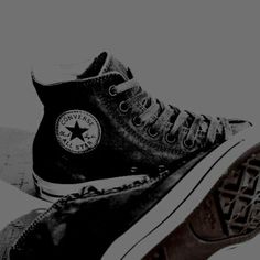 black and white photograph of two pairs of converse shoes on the ground, one with an eye patch