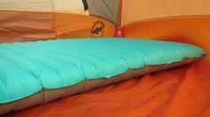 an inflatable mattress sitting on top of a bed next to a sleeping bag