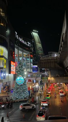 a christmas tree is lit up in the middle of a busy street