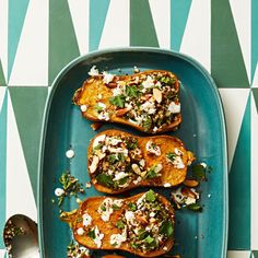 two stuffed sweet potatoes sitting on top of a baking pan covered in cheese and herbs