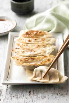 dumplings on a white plate with chopsticks