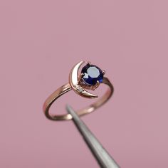 a close up of a ring with a blue and white stone in it on a pink background