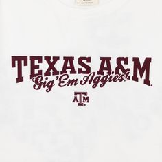 Show your Aggie pride with this Texas A&M Aggie Values T-Shirt. The white t-shirt features the iconic phrase "Texas A&M Gig 'Em Aggies" in bold maroon letters, along with maroon graphics in the shape of Texas representing everything Aggies stand for. Wear it with passion and show your love for your school! - Brand: Comfort Wash - 100% Cotton - Machine Wash Cold/Tumble Dry Low Cotton Slogan T-shirt For Fan Gear, White Short Sleeve Top With University Logo, White Tops With University Logo For Game Day, White Slogan T-shirt For College, Collegiate White T-shirt With University Logo, Collegiate Cotton T-shirt With Slogan, White University Logo T-shirt For Game Day, White University Logo T-shirt With Crew Neck, College Fan Apparel T-shirt With Slogan