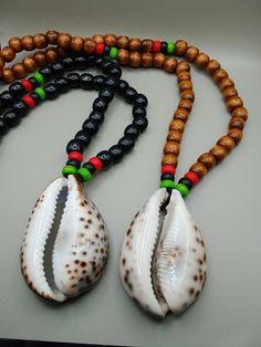 The wooden beaded large Cowrie shell necklace has a Pan African design. The options is either a black beaded necklace or brown. Each design is pictured. The necklace is approximately 28 inches long. It closes with a clasp. It is beaded with 8 to 11 mm. The cowrie shell have  is approximately 3 inches long and 2 inches wide. If you have any questions please feel free to contact us at anytime. Cowrie Shell Beaded Necklace, Handmade Casual Cowrie Shell Necklace, Handmade Brown Cowrie Shell Jewelry, Traditional Handmade Beaded Cowrie Shell Necklace, Beaded Cowrie Shell-shaped Jewelry, Cowrie Shell Necklace, Wooden Bead Necklaces, African Necklace, Black Bead Necklace