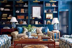 a living room filled with blue and white furniture next to bookshelves covered in pictures