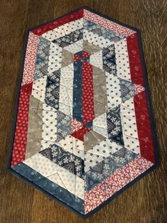 a red, white and blue quilt on a wooden table with a hexagonal design