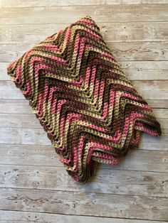 a crocheted dishcloth is laying on a wooden surface with wood planks