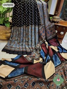 Update! - Zynah covered by LBB - https://lbb.in/bangalore/zynah-designs-handloom-sarees/ Collection: Daastaan-e-Ajrakh Introducing our Black Ajrakh Modal Silk Saree, a masterpiece of heritage and sustainability. Crafted with the timeless art of hand block printing and dyed with 100% natural hues, this saree is more than fabric; it's a piece of history. Elevate your style with eco-conscious elegance. Shop now and make a lasting fashion statement with tradition and grace. About The Craft: Ajrakh Craft, rooted in Gujarat and Rajasthan, India, is a heritage-rich textile tradition celebrated for its intricate hand block printing and 100% natural dyes. Derived from "Azrak," meaning blue, the craft boasts a stunning range of colors and symmetrical patterns. Artisans meticulously carve wooden bloc Bohemian Black Saree With Kalamkari Print, Black Bohemian Unstitched Blouse Piece, Resist Printing, Sarees Collection, Handcrafted Bags, Rajasthan India, Timeless Art, Block Printing, Co Ord Set