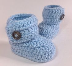 a pair of blue crocheted baby booties with buttons on the front and side