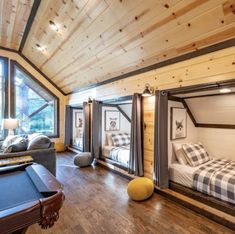 a room with a pool table, couch and bunk bed in it that is made out of wood