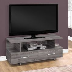 a flat screen tv sitting on top of a wooden entertainment center next to a purple wall