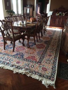 a dining room table with chairs and rug on the floor in front of an open window