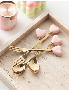 three forks and two spoons on a tray with candy hearts in the middle, next to a canister