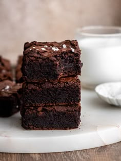 three chocolate brownies stacked on top of each other next to a cup of coffee