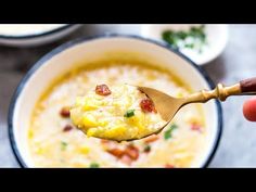 a person holding a spoon full of soup with bacon and cheese in it, while another bowl is filled with other food