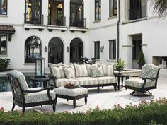 an outdoor living area with couches and chairs in front of a large white building