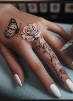 a woman's hand with a rose and butterfly tattoo on it