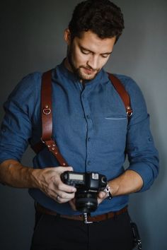 a man wearing suspenders and holding a camera