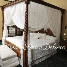 a four poster bed with white drapes on it's headboard and foot board