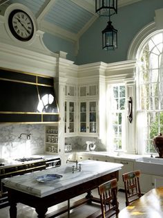 an old fashioned kitchen with large windows and wooden table in front of the stove top