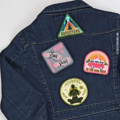 the back of a denim jacket with patches on it, including an embroidered badge and a sticker that says adventure