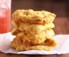 three fried food items stacked on top of each other in front of a glass of orange juice