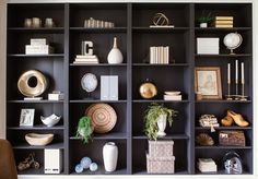 a black bookcase filled with lots of books and vases on top of it