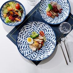 three plates with different types of food are on a blue and white place mat next to silverware