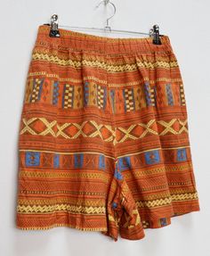 "a vintage orange and blue geometric patterned shorts ✿ IMPORTANT INFORMATION: * excellent vintage condition * size: small - please check exact measurements below (they're there for your benefit!) * hip pockets ✿ MEASUREMENTS (taken while item is lying flat, some measurements will need to be doubled): * waist: 12-15\" (30-38cm) - elasticated * hips: 22\" (56cm) * front rise: 13.5\" (34cm) * back rise: 16\" (41cm) * leg in-seam: 4\" (10cm) * leg out-seam: 16\" (41cm) * thigh width: 13.5\" (34cm) Brown Bohemian Shorts, High-waisted Orange Shorts For Vacation, Multicolor Bottoms With Geometric Pattern For Summer, Vintage Bermuda Bottoms With Built-in Shorts, Retro Short Bottoms For Vacation, Vintage Multicolor Short Bottoms, Vintage Multicolor Short Length Bottoms, Summer Vintage Bottoms With Retro Print, Retro Orange Bottoms With Pockets