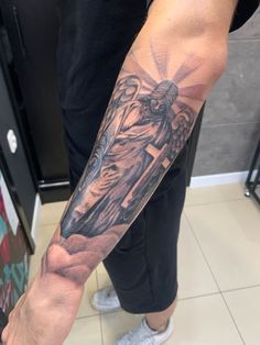 a man with a cross and angel tattoo on his arm