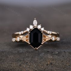 an engagement ring with a black stone surrounded by white and clear stones on top of a rock