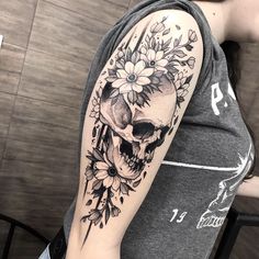 a woman with a skull and flowers tattoo on her arm