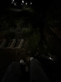 the person is sitting in the dark with their feet on the ground at night time