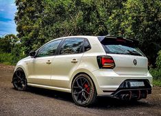 the rear end of a white volkswagen car parked in front of some trees and bushes