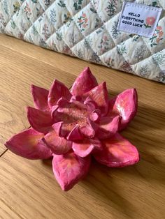 a pink flower sitting on top of a wooden table