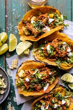 four tacos on a cutting board with limes and avocados around them