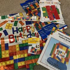 several birthday cards are laid out on the floor next to some construction paper and legos