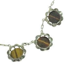 This is part of Chairish’s Fine Jewelry assortment.  1940s sterling & tigers eye necklace. Tigers eye cabochons in Belcher settings are connected by paper-clip chain and finished w/ fine chain and a hook-and-push clasp. These are some of the most gorgeous tigers eye stones I've ever encountered -- rich shades of chocolate brown and warm gold, and oh, the movement! Bands of color and light play across the faces of the stones like sunlight in a dark forest. Exquisite workmanship and impeccable con Retro Soldered Metal Jewelry, Retro Round Cabochon Jewelry, Retro Cabochon Jewelry, Mid-century Adjustable Silver Jewelry, Vintage Sterling Silver Link Jewelry, Vintage Round Pendant Necklace With Polished Finish, Vintage Brown Jewelry With Polished Finish, Vintage Brown Nickel-free Necklace, Elegant Brown Soldered Jewelry