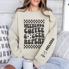 Stay cozy and stylish on the sidelines with our personalized soccer mom crewneck sweatshirt! The front features a retro-inspired "weekends, coffee, soccer, repeat" text, perfect for every soccer mom out there. On the left sleeve, you'll find a design showcasing your kid's name and their jersey number, adding a special touch to this already unique piece. Whether you're cheering on your little star or running errands, this sweatshirt is a must-have for any soccer mom who wants to show off their pr White Crew Neck Sweatshirt For Weekend, Letter Print Sweatshirt For Fall Weekend, Sporty Letter Print Tops For Weekend, Sporty Weekend Tops With Letter Print, Sporty Tops With Letter Print For Weekend, Sporty Cotton Tops With Letter Print For Weekend, White Long Sleeve Sweatshirt For Weekend, Sporty Graphic Print Sweatshirt For Weekend, Weekend White Crew Neck Sweatshirt