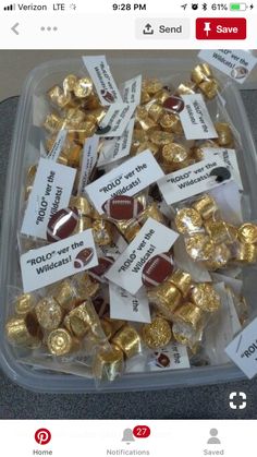 a plastic container filled with lots of gold and chocolate candies on top of a table