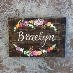 a wooden sign with flowers painted on it