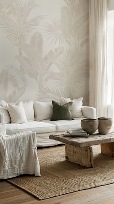 a living room with white furniture and wallpaper on the walls, along with a large wooden coffee table