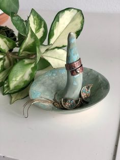 a ceramic figurine sitting on top of a plate next to a potted plant