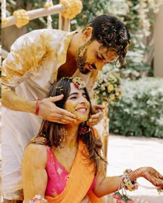 a man is shaving a woman's face with yellow paint