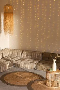 a living room filled with lots of furniture next to a wall covered in string lights